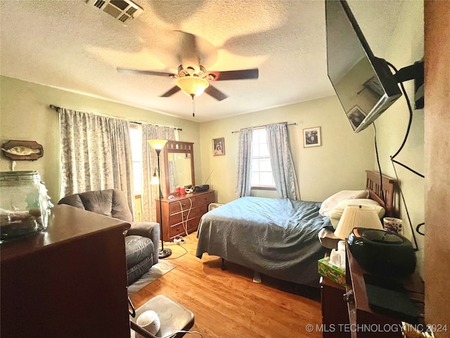 bedroom featuring ceiling fan, a textured ceiling, and light hardwood / wood-style flooring