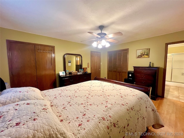 bedroom featuring ceiling fan, multiple closets, and light hardwood / wood-style flooring