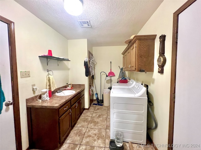 laundry room featuring cabinets, sink, washing machine and dryer, a textured ceiling, and light tile patterned flooring