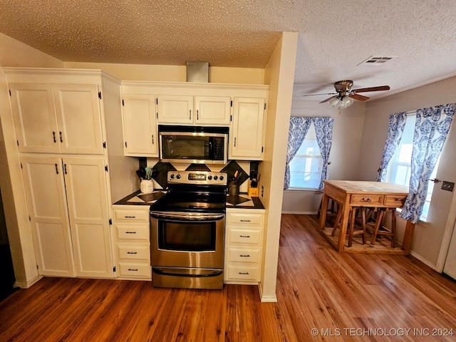 kitchen with white cabinets, hardwood / wood-style floors, a textured ceiling, and stainless steel appliances