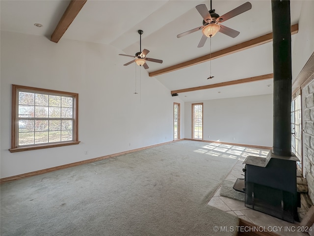 unfurnished living room featuring light colored carpet, ceiling fan, high vaulted ceiling, beamed ceiling, and a wood stove