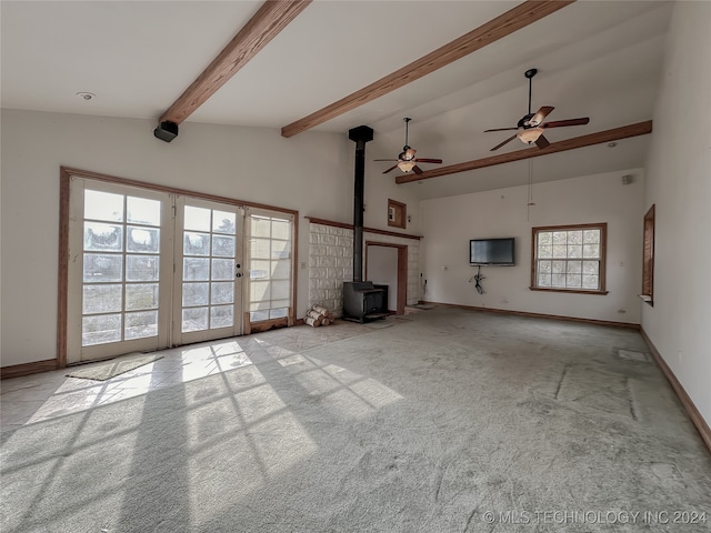 unfurnished living room with light carpet, ceiling fan, high vaulted ceiling, beamed ceiling, and a wood stove