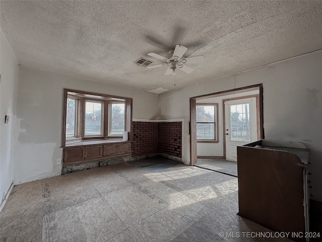 unfurnished room with ceiling fan, plenty of natural light, and a textured ceiling