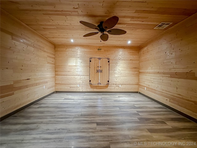 spare room with wood-type flooring, ceiling fan, wood ceiling, and wood walls