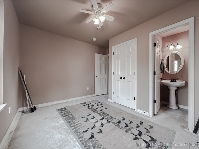 bedroom featuring a closet, ensuite bathroom, sink, and ceiling fan