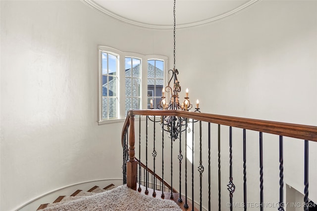 stairs featuring ornamental molding and an inviting chandelier