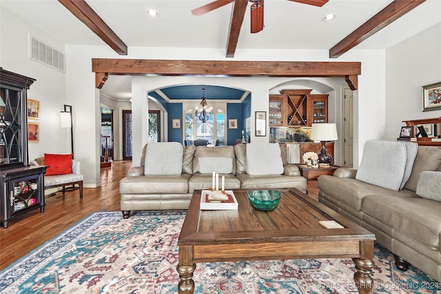 living room featuring beam ceiling, ornamental molding, ceiling fan with notable chandelier, and hardwood / wood-style flooring