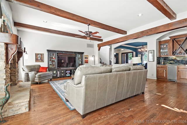 living room featuring beamed ceiling, hardwood / wood-style floors, ceiling fan with notable chandelier, and bar