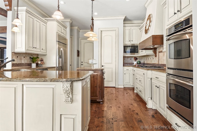 kitchen with sink, hanging light fixtures, dark hardwood / wood-style floors, dark stone countertops, and built in appliances