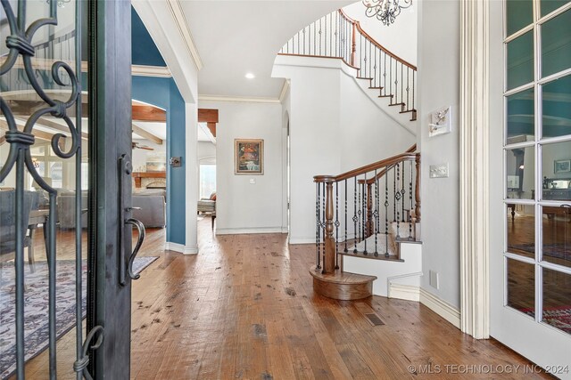 entryway featuring hardwood / wood-style flooring, an inviting chandelier, and crown molding