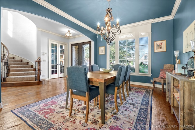 dining space featuring french doors, hardwood / wood-style flooring, an inviting chandelier, and ornamental molding