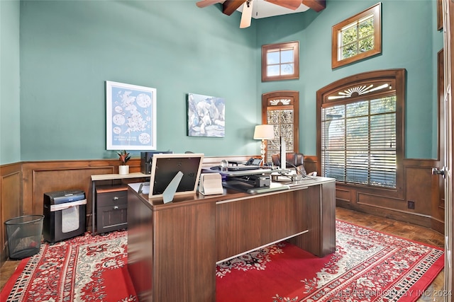 home office with a high ceiling, ceiling fan, and dark wood-type flooring