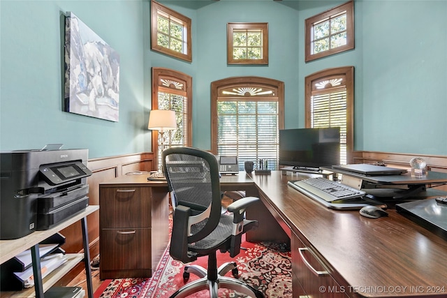 office area with hardwood / wood-style floors, a healthy amount of sunlight, and a towering ceiling