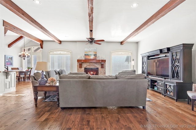 living room with beam ceiling, dark hardwood / wood-style flooring, a stone fireplace, and a healthy amount of sunlight