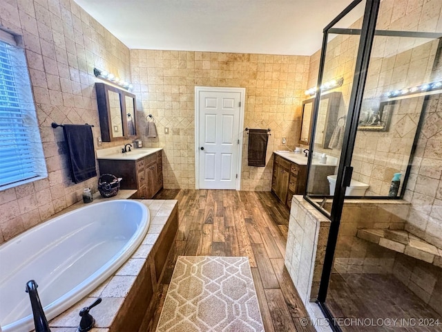 bathroom with hardwood / wood-style floors, vanity, tile walls, and plus walk in shower