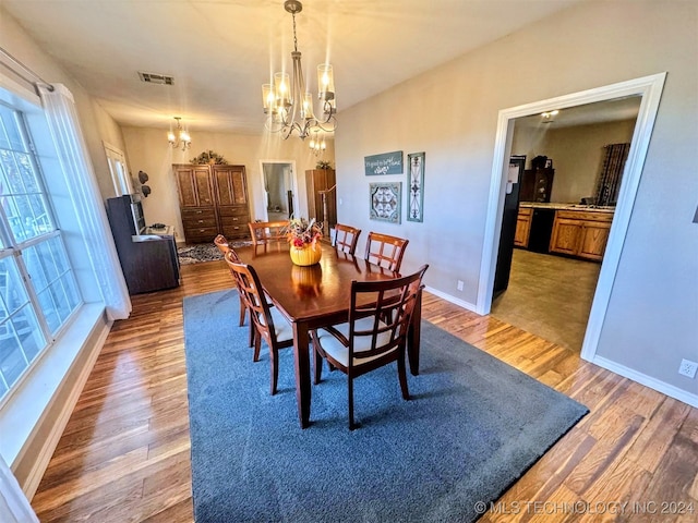 dining space with wood-type flooring and an inviting chandelier