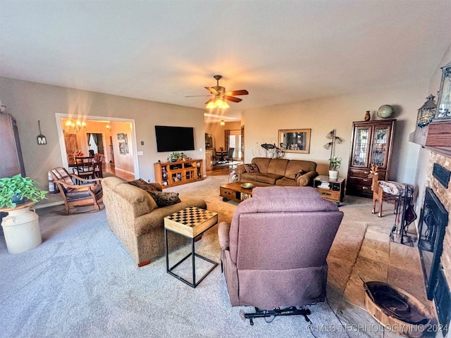 living room with a stone fireplace, light carpet, and ceiling fan with notable chandelier