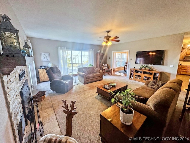 living room with a textured ceiling, ceiling fan, and a fireplace