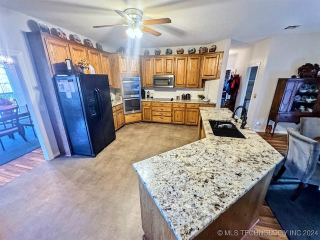 kitchen featuring light carpet, ceiling fan with notable chandelier, sink, appliances with stainless steel finishes, and light stone counters