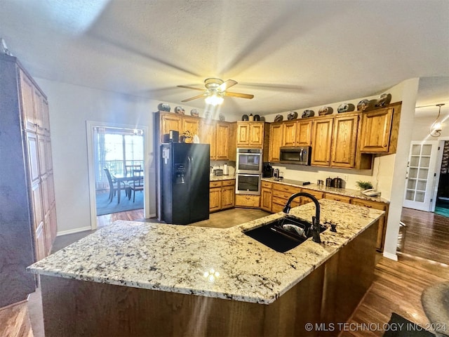 kitchen featuring dark wood-type flooring, sink, ceiling fan, light stone countertops, and appliances with stainless steel finishes