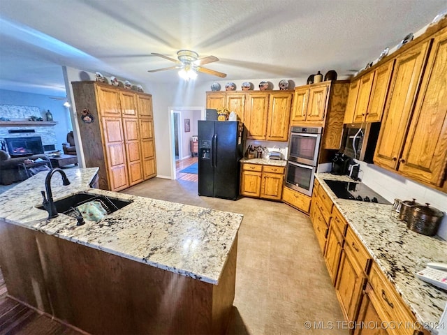 kitchen featuring light stone countertops, a textured ceiling, ceiling fan, sink, and black appliances