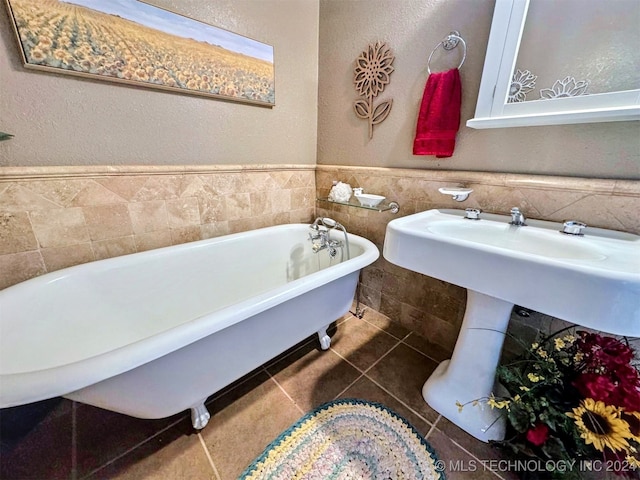 bathroom with a washtub, tile patterned floors, and tile walls