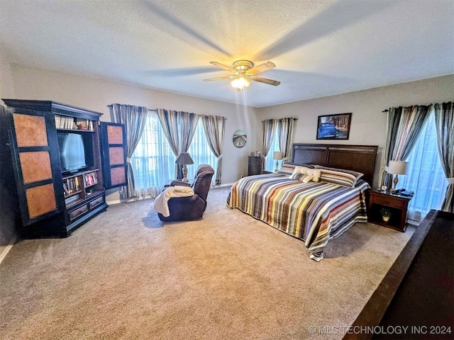 carpeted bedroom with ceiling fan and a textured ceiling