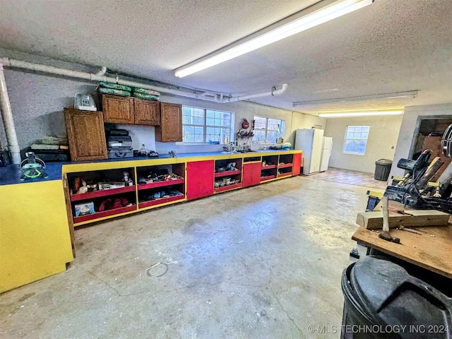 garage with a workshop area and white fridge