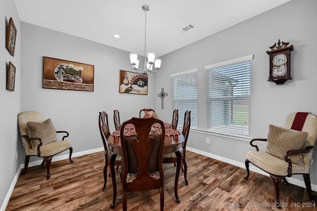 dining space with dark wood-type flooring and a notable chandelier