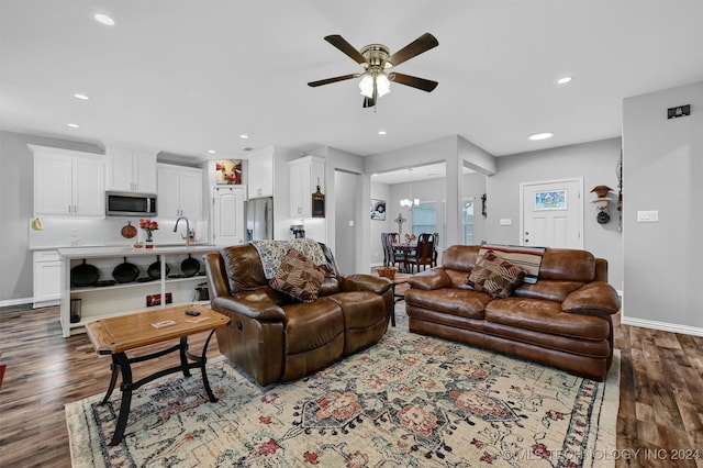 living room with ceiling fan with notable chandelier, dark hardwood / wood-style floors, and sink