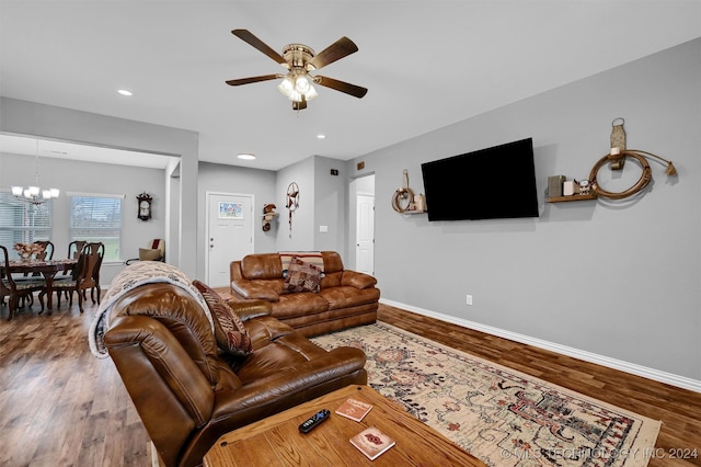 living room with hardwood / wood-style floors and ceiling fan with notable chandelier