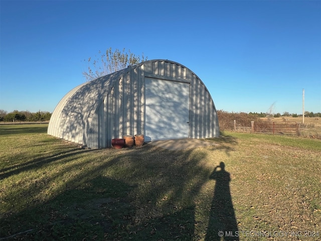 view of outdoor structure with a garage, a rural view, and a yard