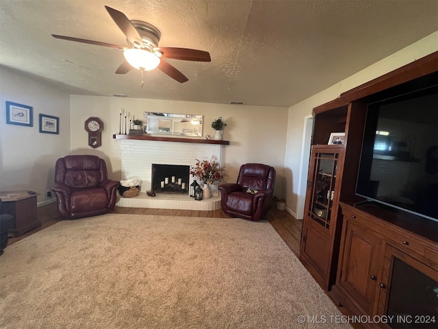 carpeted living room featuring a fireplace, a textured ceiling, and ceiling fan