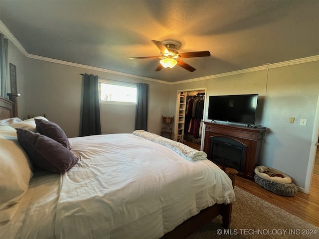 bedroom featuring crown molding, hardwood / wood-style flooring, ceiling fan, a spacious closet, and a closet