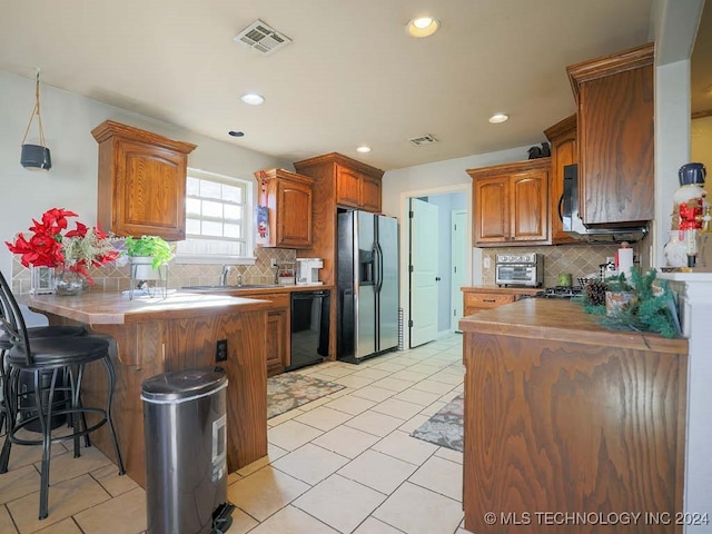 kitchen featuring dishwasher, stainless steel fridge, kitchen peninsula, and backsplash