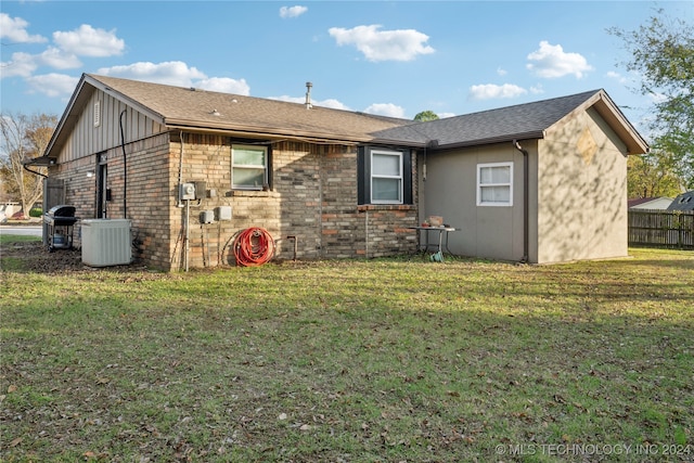 rear view of property featuring a yard and cooling unit