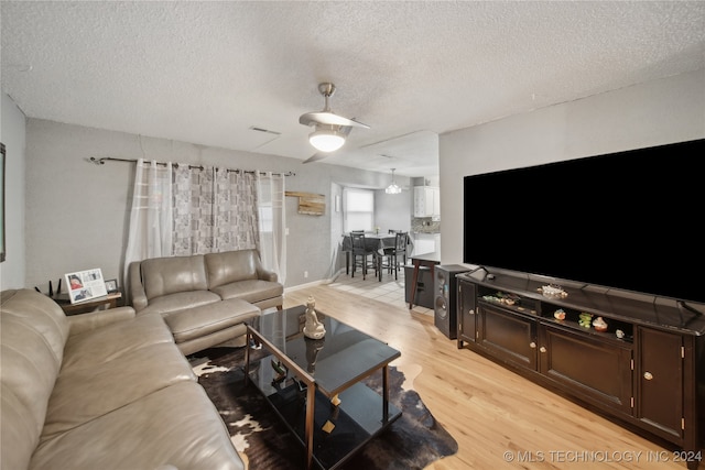 living room featuring an inviting chandelier, a textured ceiling, and light wood-type flooring