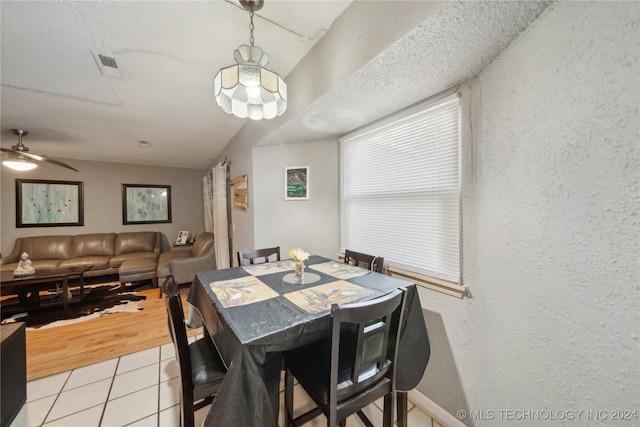 tiled dining room with a textured ceiling, vaulted ceiling, and ceiling fan