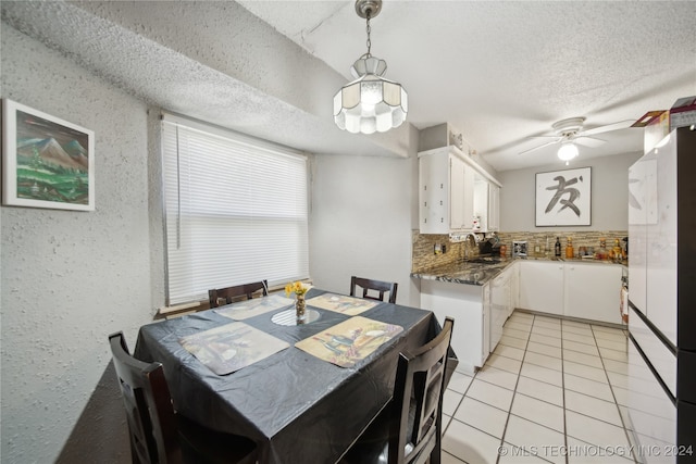 tiled dining space with ceiling fan, sink, and a textured ceiling