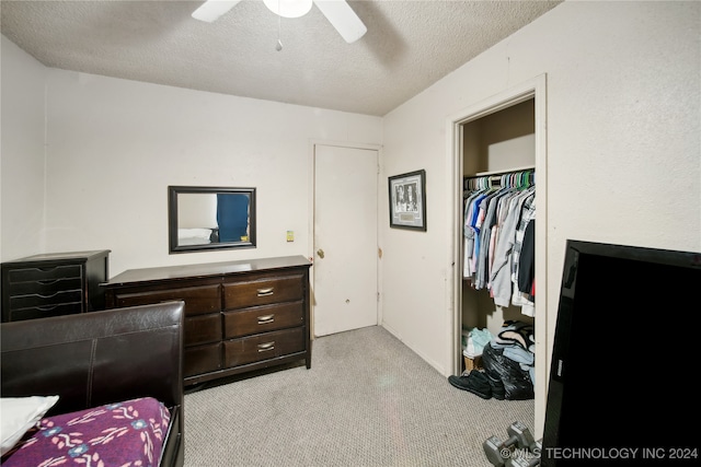 carpeted bedroom with ceiling fan, a textured ceiling, and a closet