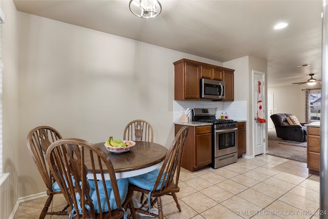 kitchen with backsplash, ceiling fan, light stone countertops, light tile patterned floors, and appliances with stainless steel finishes