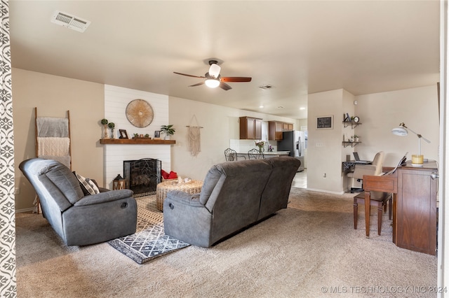 living room featuring carpet flooring, ceiling fan, and a large fireplace