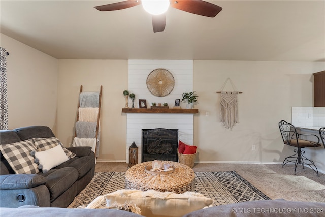 carpeted living room with ceiling fan and a large fireplace