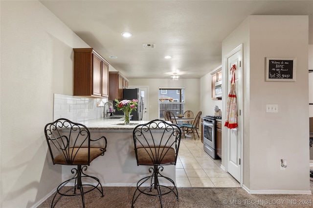 kitchen featuring sink, light tile patterned floors, appliances with stainless steel finishes, tasteful backsplash, and kitchen peninsula