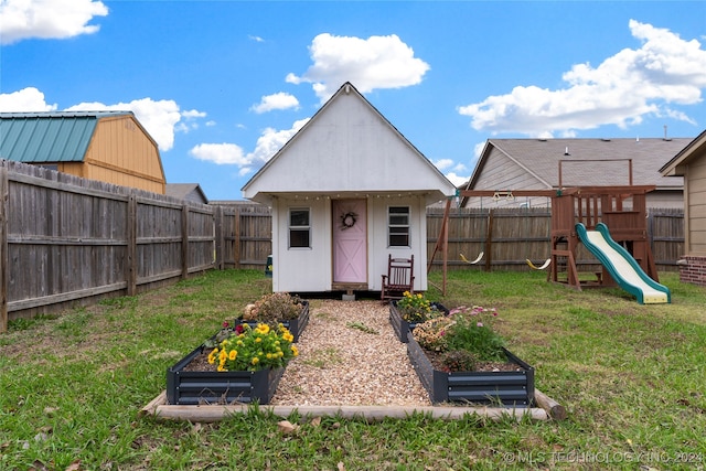 rear view of house featuring an outbuilding, a yard, and a playground