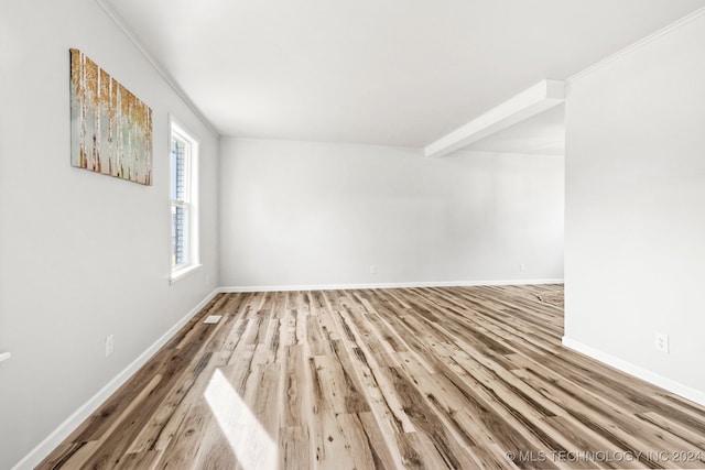 empty room featuring wood-type flooring and ornamental molding