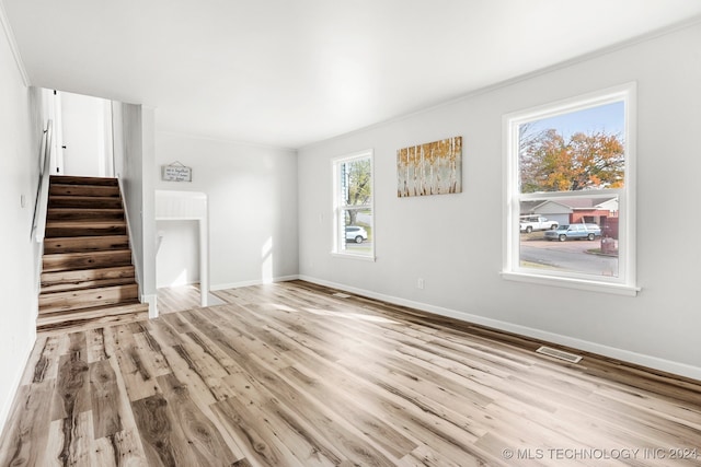 unfurnished living room featuring light hardwood / wood-style floors, plenty of natural light, and ornamental molding