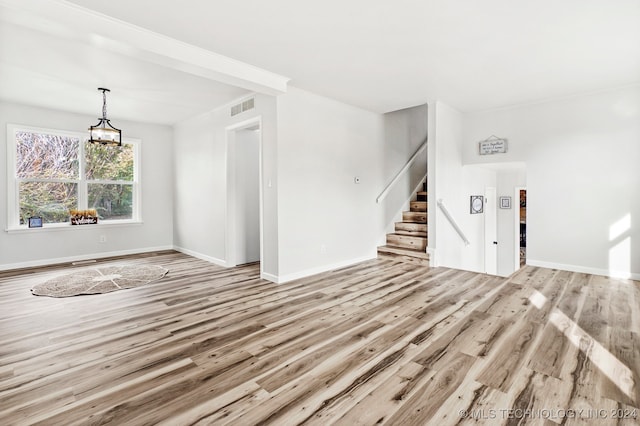 unfurnished living room featuring light wood-type flooring and crown molding