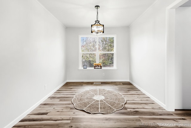 unfurnished room featuring hardwood / wood-style floors, a notable chandelier, and crown molding