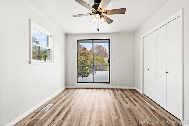 unfurnished bedroom featuring ceiling fan, light wood-type flooring, and multiple windows